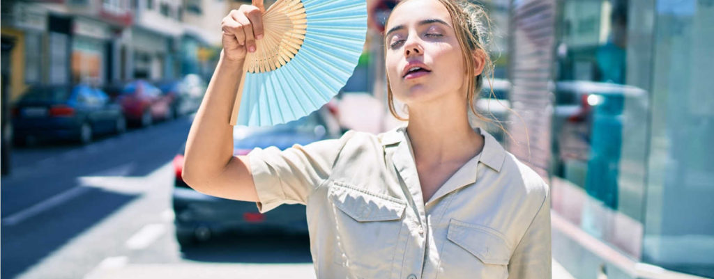 A woman using hand fan to cool down her face