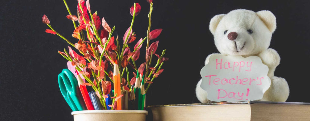 A display of flowers, book, and a teddy bear for teacher