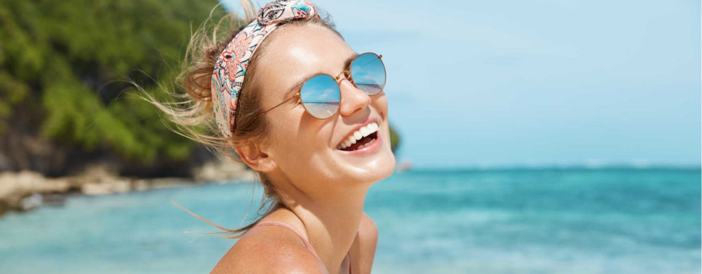 A woman at the beach smiling.