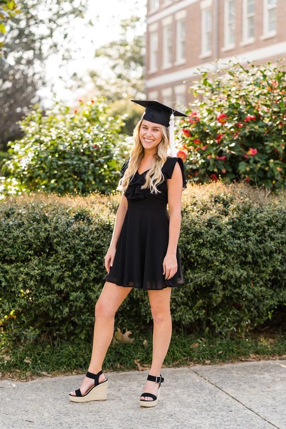 A young graduate wearing a black dress and black cap.