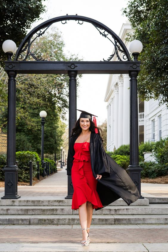 Young woman wearing a red dress with graduation cap and gown.