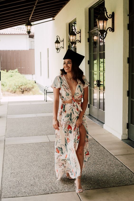 A young graduate wearing a long floral dress and a cap.