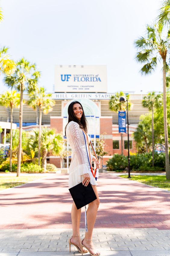 A young woman wearing a white dress in front of University of Florida University.