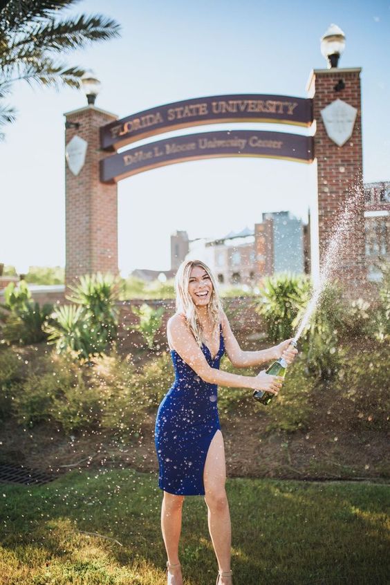 A woman wearing navy summer dress holding a bottle of champagne.