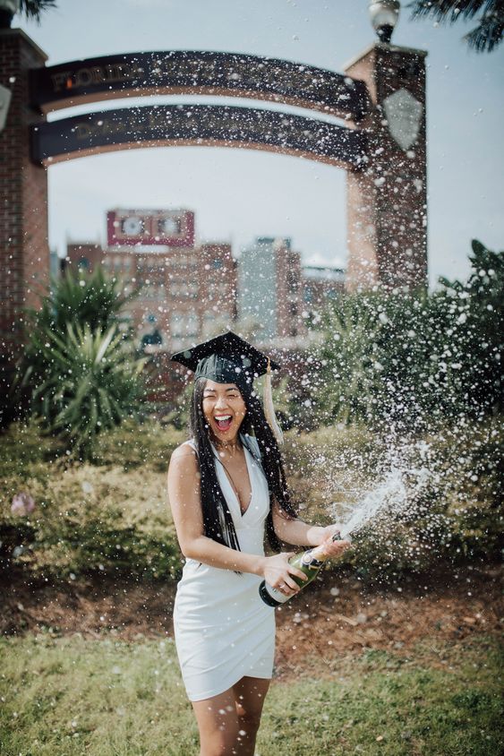 A young woman wearing a white dress and a black graduation cap.