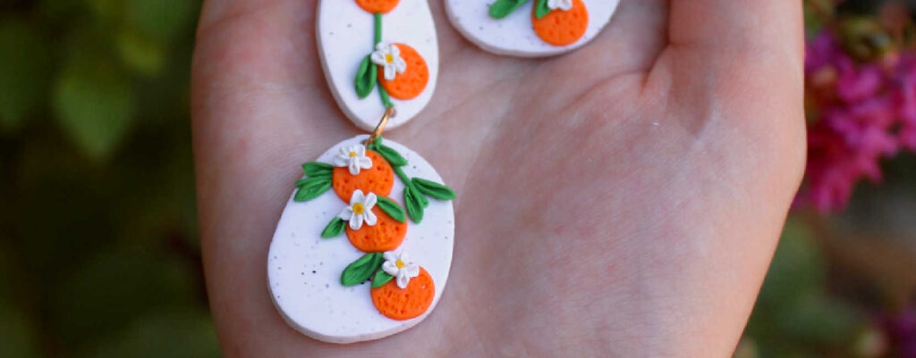 A pair of polymer clay earrings on a palm of a hand.