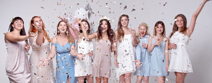 A bunch of young woman graduates celebrating with balloons and drinks.