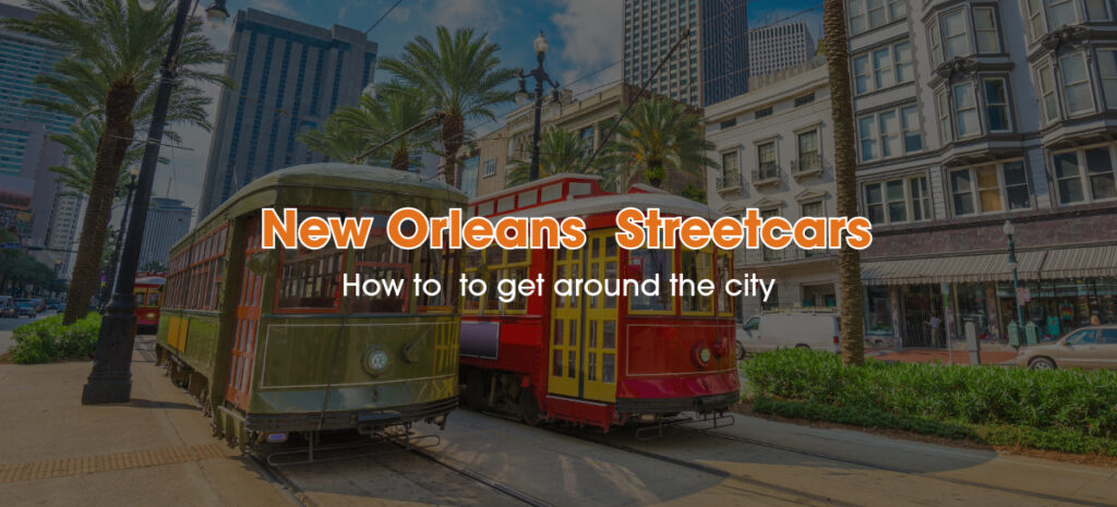 A couple of New Orleans' Streetcars are passing through the street between palm trees and tall buildings.