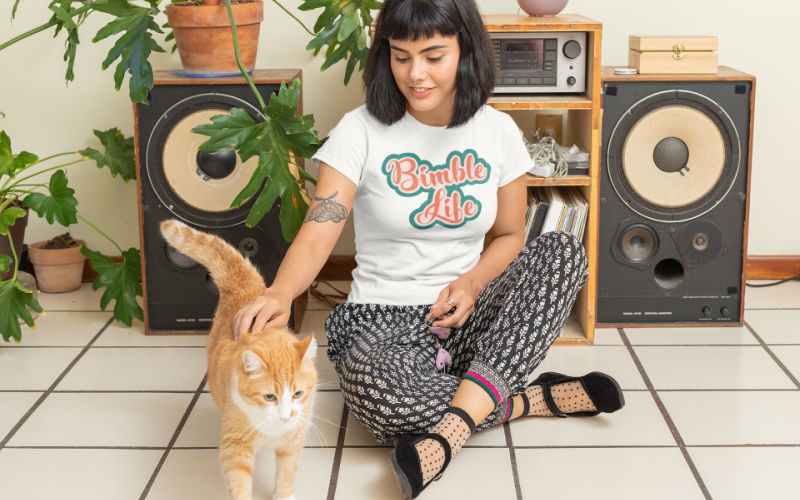 A woman wearing BimbleLife t-shirt sitting with a cat.