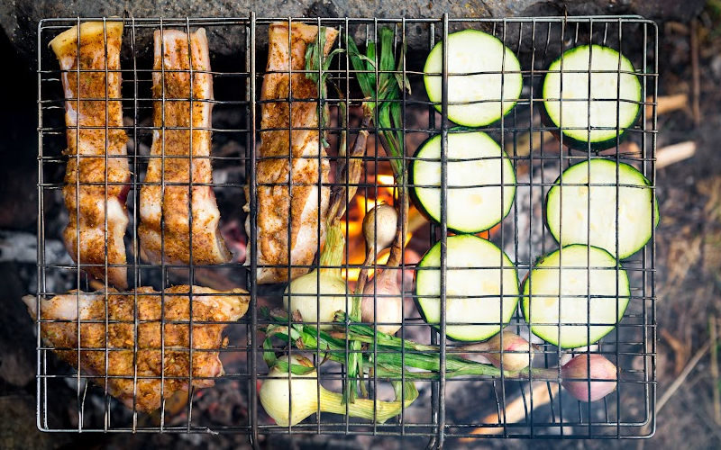 Marinated chicken strips and veggie slices on the open fire grill