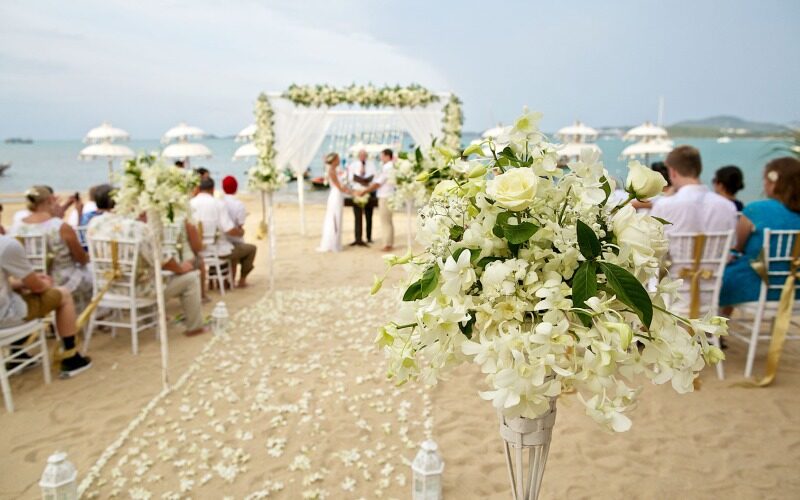 A beach wedding with flowers and guests.