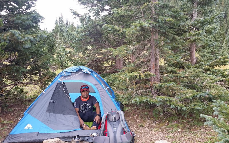 A man sitting inside of a tent in the mountains.