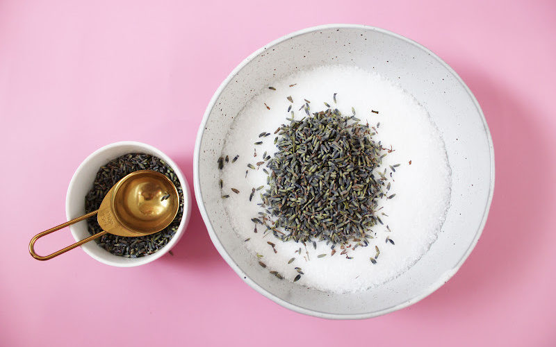 A bowl of lavender buds and Epsom salt with a gold measuring spoon