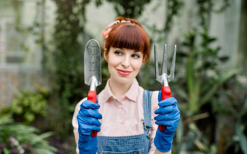 A woman holding gardening tools