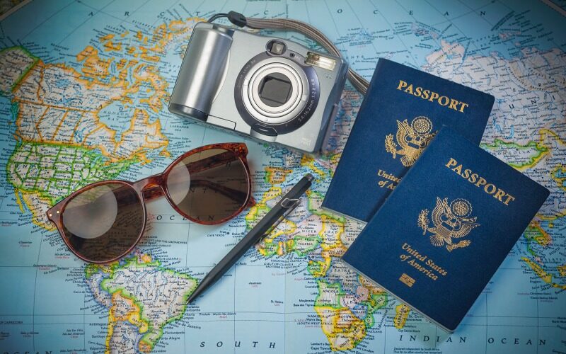 A couple of US passports, camera, and sunglasses placed on a world map.