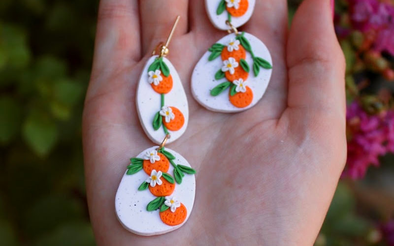 A pair of polymer clay earrings on a palm of a hand.