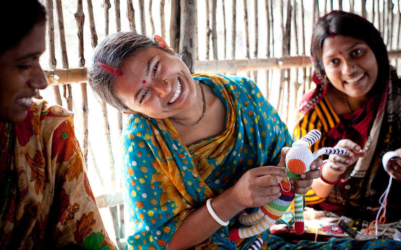 Women artisans in Bangladesh crafting and smiling.