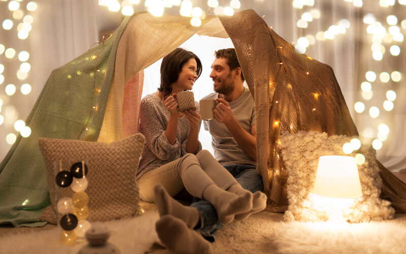 A couple sitting under tent with string lights.