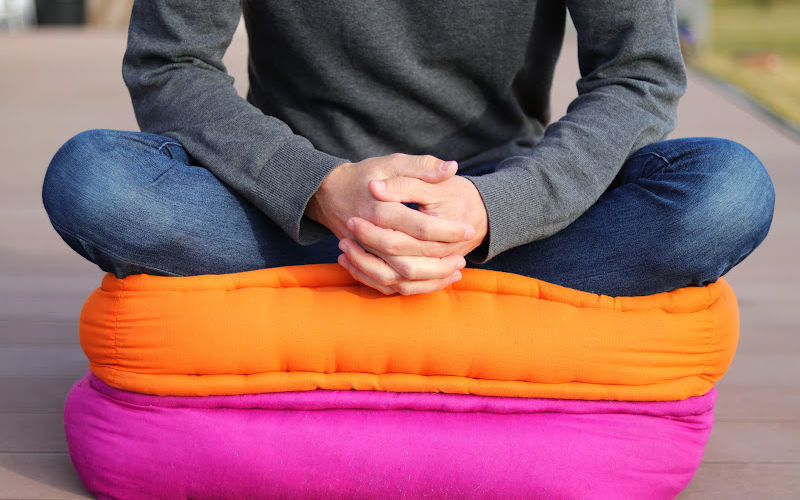 A person sitting on a couple of colorful floor cushions