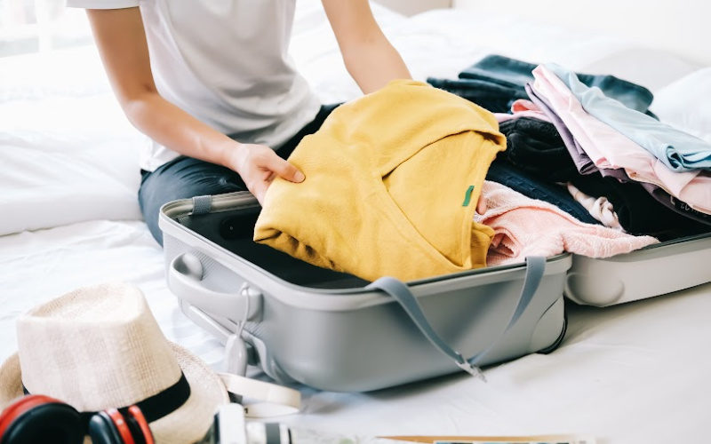 Packing suitcase with clothing.